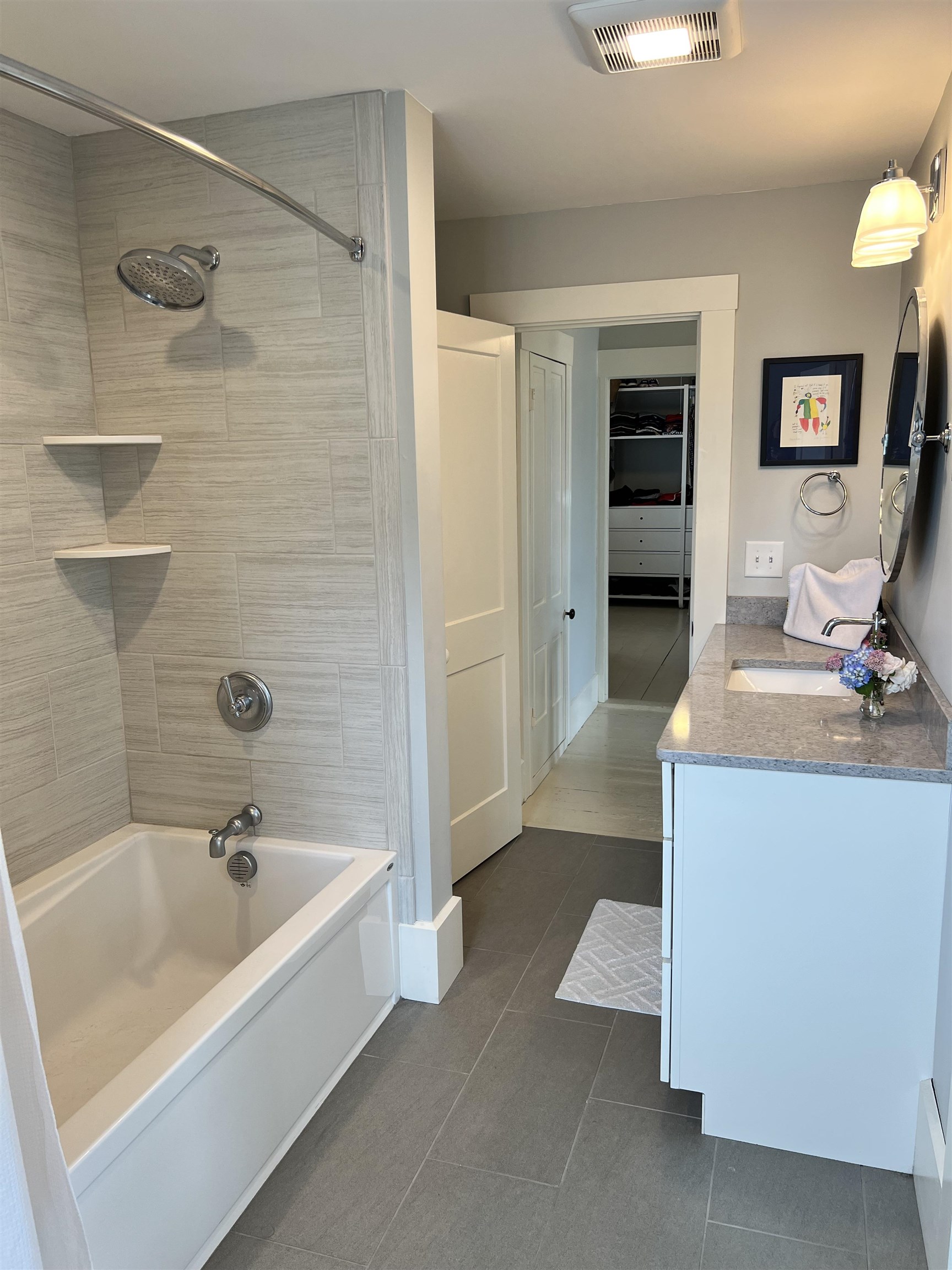 Three bedrooms share this beautiful tiled tub/shower bathroom, with quartz counters, and a white shaker vanity.