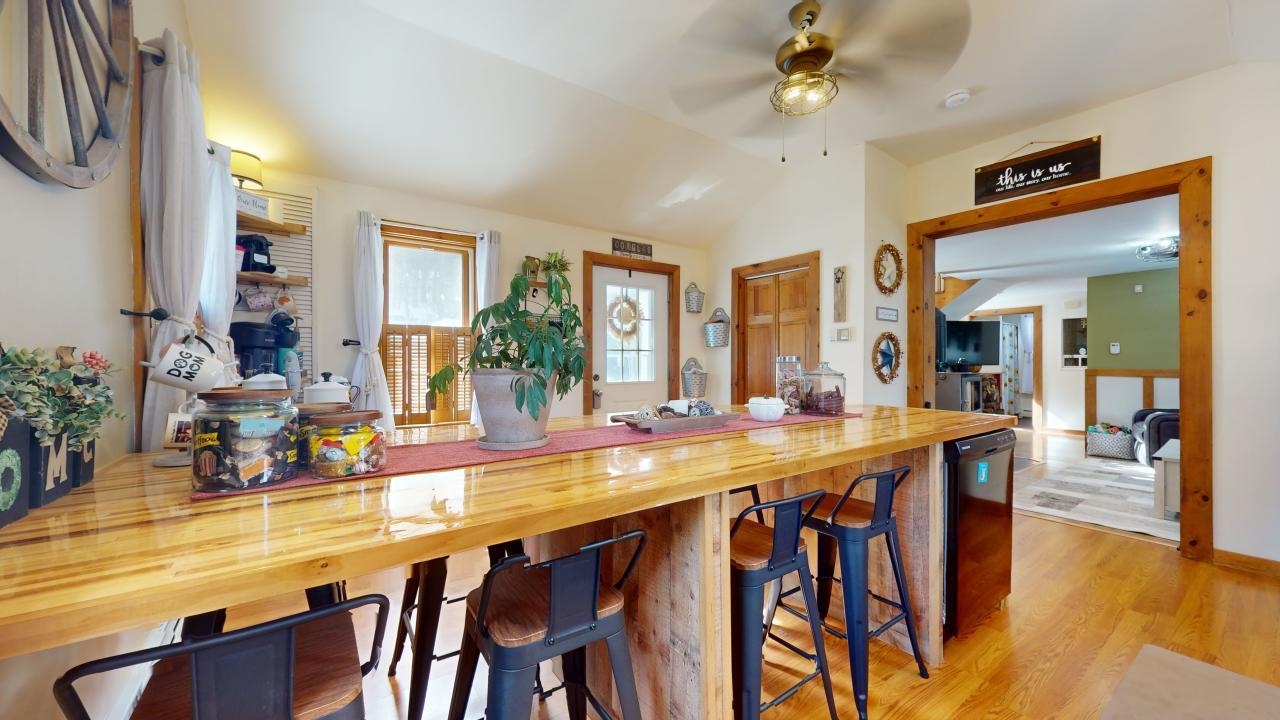 Kitchen with ceiling fan, wooden counters, light hardwood / wood-style flooring, a breakfast bar area, and lofted ceiling