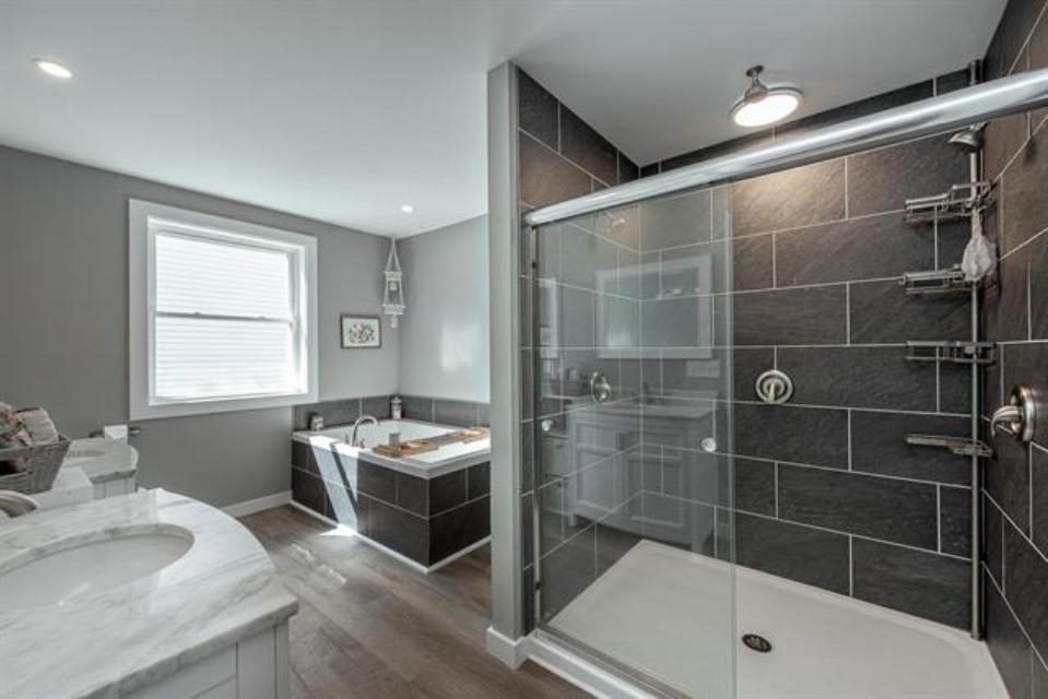 primary bathroom featuring a soaking tub, double vanities and oversized tiled shower
