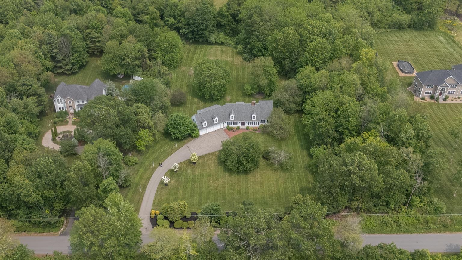 Price Improvement! Discover exceptional value at 40 Lane Road, Derry, NH. This beautifully expanded Cape boasts nearly 5,000 square feet of thoughtfully designed living space, ideal for comfort, privacy, and flexibility. With two primary suites—one on the main level and an expansive second suite above the oversized 3-car garage—this home is perfectly suited for multi-generational living or private guest quarters. Set on 3 acres of mature landscaping, the property offers a serene, park-like setting that's perfect for entertaining, gardening, or simply unwind Step inside to an open-concept floor plan filled with natural sunlight. The spacious kitchen flows effortlessly into the living room, where soaring ceilings and a dramatic catwalk add architectural interest and a sense of grandeur. Other notable features include a lower level theater room, a first floor office with double-sided fireplace, an inviting eat-in kitchen overlooking the large backyard, a generous dining room with built-ins, and vaulted ceiling living room with skylights, a double-sided fireplace, and built-in bookshelves.  A first floor laundry room, a full-house back-up generator, and 3 heating/cooling systems make for a secure and comfortable residence. Derry is known for its excellent schools and proximity to major highways, making it an attractive option. CHECK OUT THE VIRTUAL TOUR!