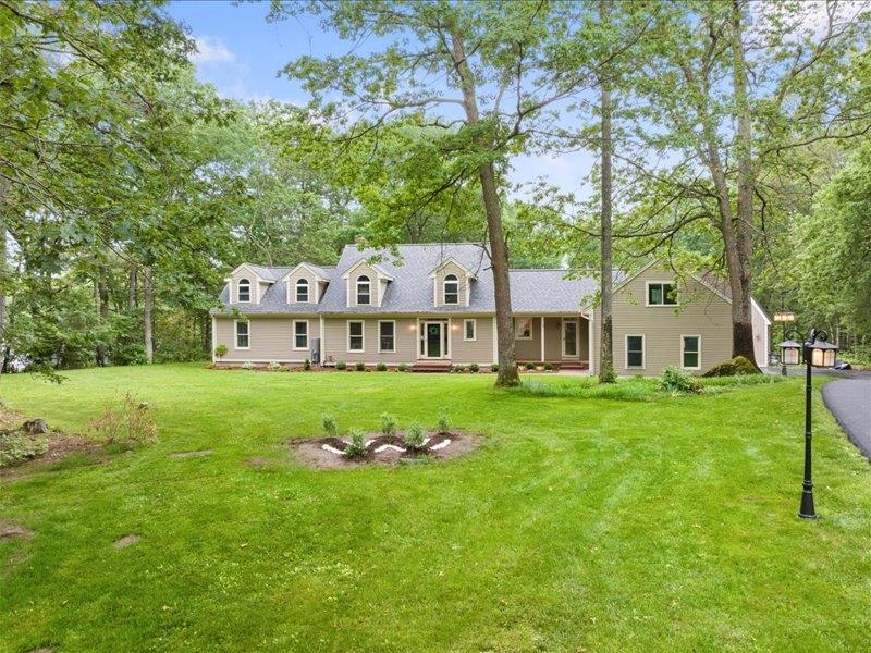 Expansive cape renovated with many upgrades. Recently installed state-of-the-art heat pump heat/ac. 1st floor primary bedroom ensuite, whirlpool tub, new tile walk-in shower, 2 vanities/sinks, walk-in closet, engineered Acadia wood floor & slider out to deck.  Spacious formal entry foyer has cathedral ceiling plus hardwood flooring that expands throughout the dining area, office and living room. Formal Dining room has engineered bamboo flooring, skylights and access to deck .Living room w/cathedral ceiling, floor-to-ceiling brick, wood burning fireplace and slider onto large deck that overlooks the private yard.   Kitchen has vaulted ceiling, skylight, granite counters, large island with a new Thermador 5-burner cooktop, plus 2 Thermador wall ovens, a warming drawer, microwave, compactor, dishwasher. 2nd floor has 2 bedrooms, full bath, engineered Acacia wood floor. 4th bedroom is a 2-room suite accessed by stairs off the kitchen hallway includes Acacia hardwood flooring, mini-fridge, sink/cabinet, walk-in closet, 3/4 bath, tiled shower.  Lower level w/pool table room & bar including a small fridge. New laminate floors in the huge family room and office.  3 car attached garage plus a 24x24 detached garage with finished 2nd floor. Property abuts 274 acres of conservation land.  Front yard has lamp posts along the newly paved driveway, brick walkway, plantings include blueberry bushes. Back yard has 4 apple trees.   Conveniently located just minutes from route 93 exit 3.