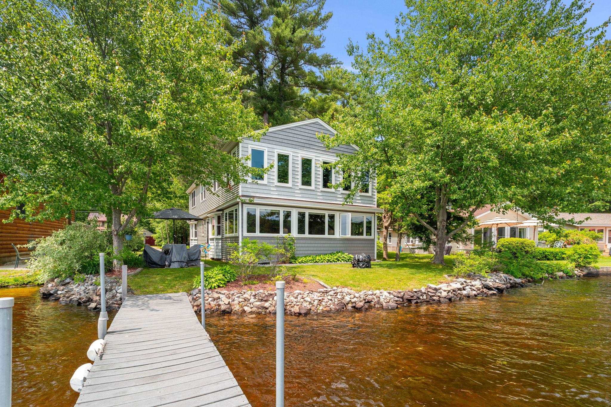 Big Island Pond Waterfront Gem – Year-Round Living with Stunning Lake Views  Experience lakefront living at its finest in this beautifully updated, year-round home on the coveted shores of Big Island Pond. With 50 feet of direct waterfront, a private dock, and a sandy-bottom shoreline, this property offers the perfect retreat for boating, swimming, and year-round recreation. Set on a level, manicured lot, this home boasts panoramic views of the lake from multiple rooms. The remodeled kitchen features granite countertops, double ovens, a tile backsplash, and radiant heat flooring. An expansive dining room is perfect for hosting gatherings, while the oversized living room features a custom-built pine fireplace with granite surround and built-in bookshelves—ideal for cozy evenings by the fire. Enjoy the beauty of every season from the three-season sunroom and appreciate the convenience of solid surface flooring throughout the first level. With three heating and air conditioning zones, comfort is easily managed in every part of the home. Additional features include a laundry chute, heat lamps in the bathroom, and a whole-house water filtration system. Nature lovers will enjoy nearby walking and snowmobile trails, and commuters will appreciate being just 50 minutes from Boston and close to Manchester Airport. Don’t miss your chance to own this exceptional waterfront property where comfort, convenience, and natural beauty come together.