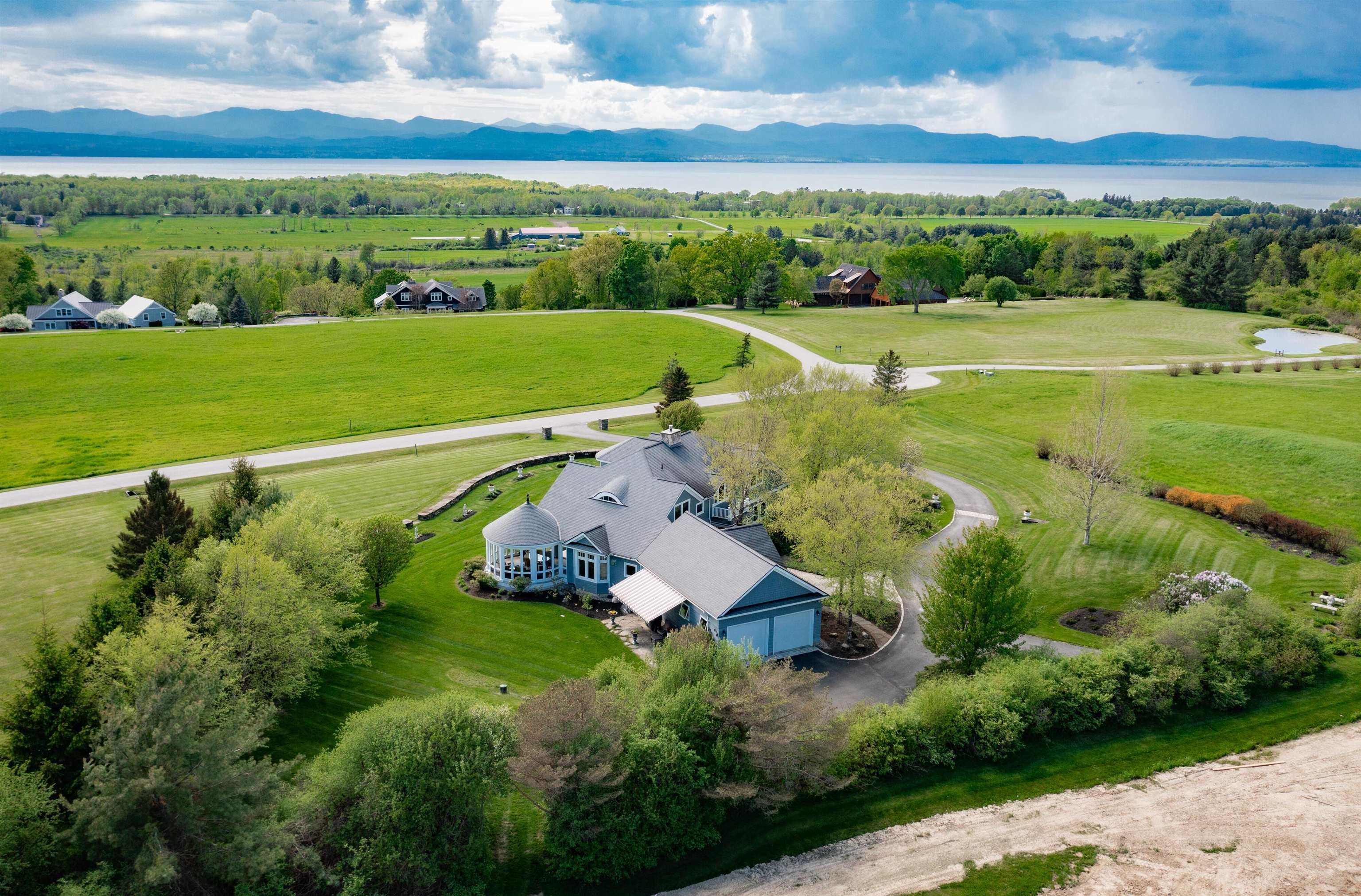 Offering panoramic sunset views over Lake Champlain and the Adirondack Mountains, 400 Crosswinds is a 3,750± sq. ft. shingle-style home set on 2.11± private acres in Charlotte’s Preserve enclave. Designed by architect Paul Ferland with interiors by Casa Bella Designs, the 3-bedroom, 2.5-bath residence features curated details including Bosse and Sapele hardwoods, a floor-to-ceiling stone fireplace, and a chef’s kitchen with SubZero and Wolf appliances. The main-level primary suite offers direct access to a covered porch with an outdoor fireplace, while additional spaces include a media room, office, exercise room with sauna, and wine cellar. Landscaped gardens, a bluestone patio, and a view easement ensure lasting connection to the surrounding natural beauty—just 9 miles from downtown Burlington.