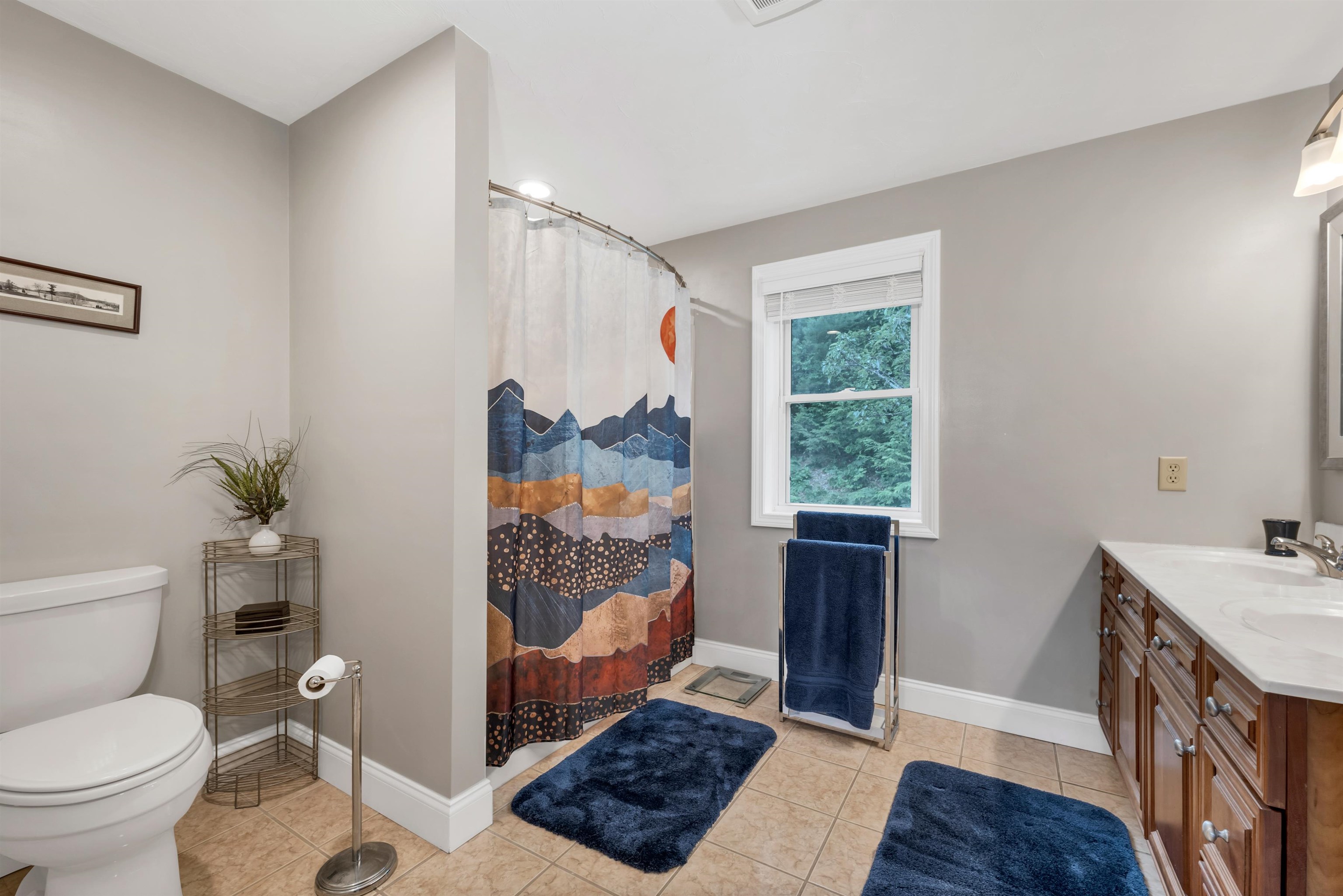 FULL PRIMARY BATHROOM WITH TILE FLOOR, WOOD VANITY AND GRANITE COUNTERS.