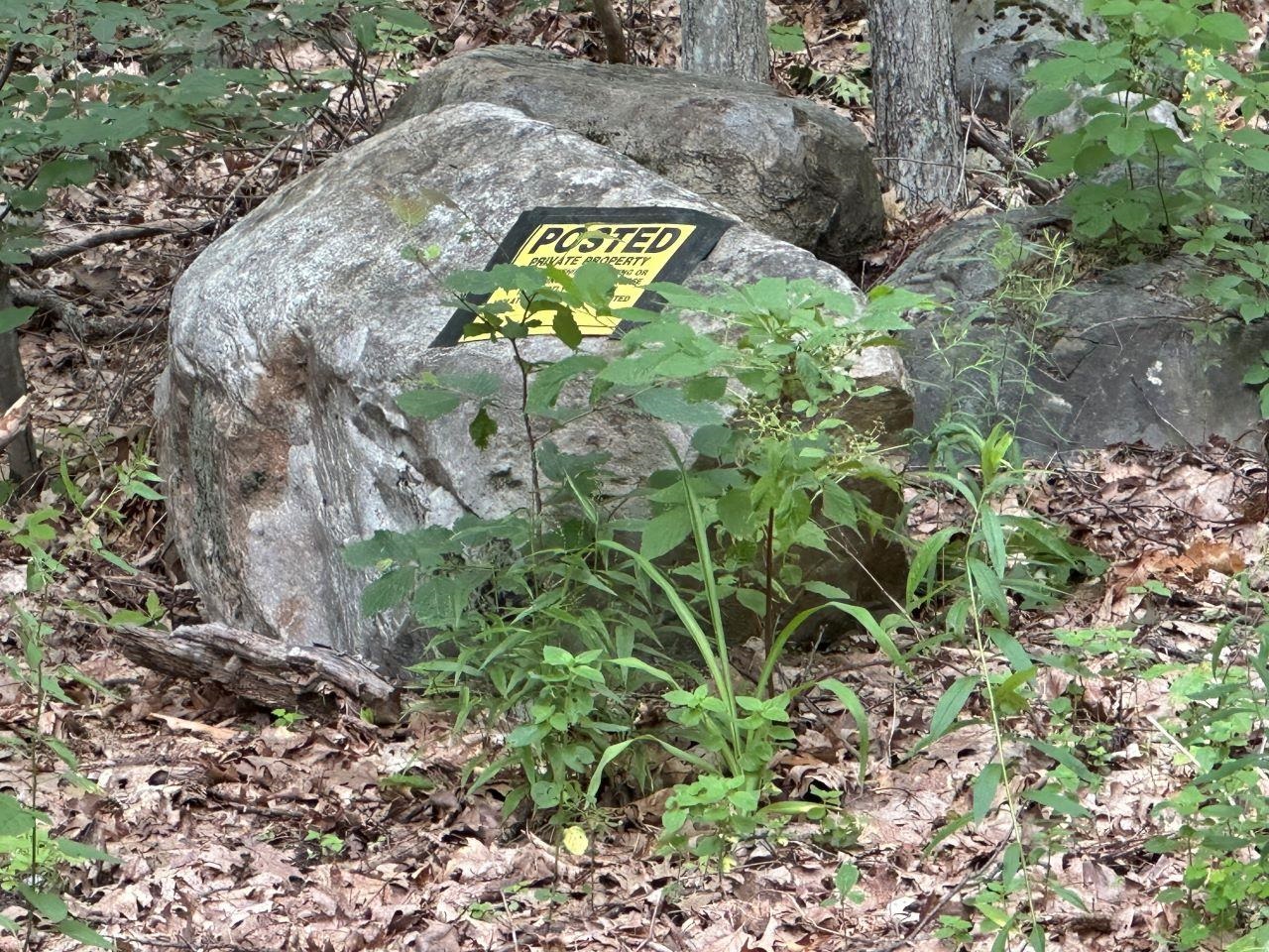 Posted sign on rock at start of access rd