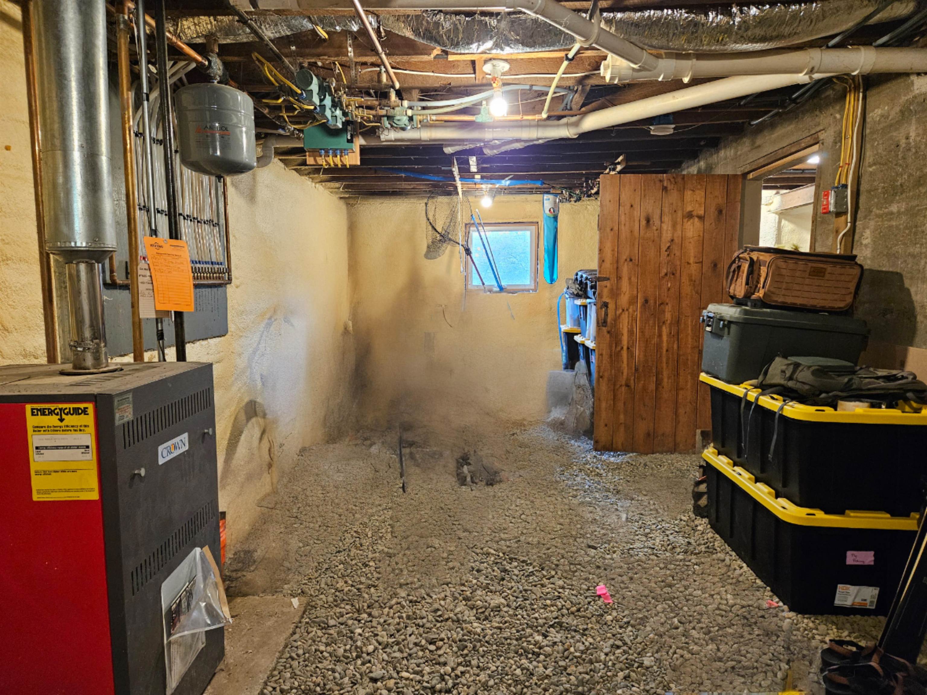Unfinished storage room in basement with hot water heater and boiler
